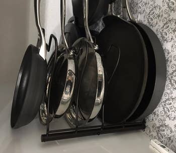 A variety of pans and lids organized in a metal rack 