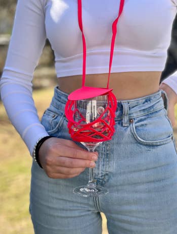 Model holding a glass of wine in the pink strap 