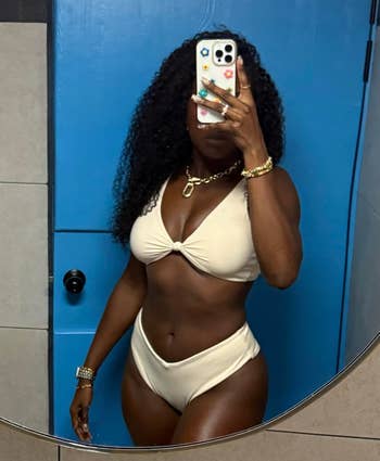 Person successful a bikini taking a reflector selfie successful a bathroom, showcasing swimwear style