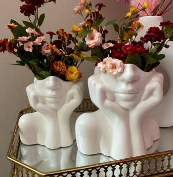 reviewer's two white ceramic head vases filled with various flowers