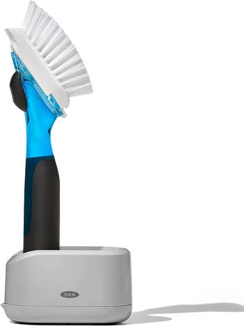 Brush with ergonomic handle holding soap inside of it in a stand