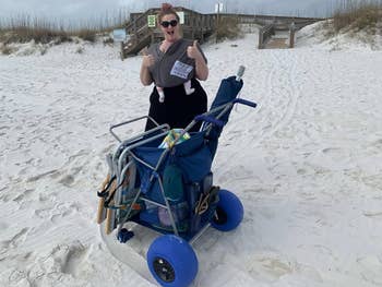 Reviewer on beach with the cart, giving a thumbs up. Cart is loaded with items