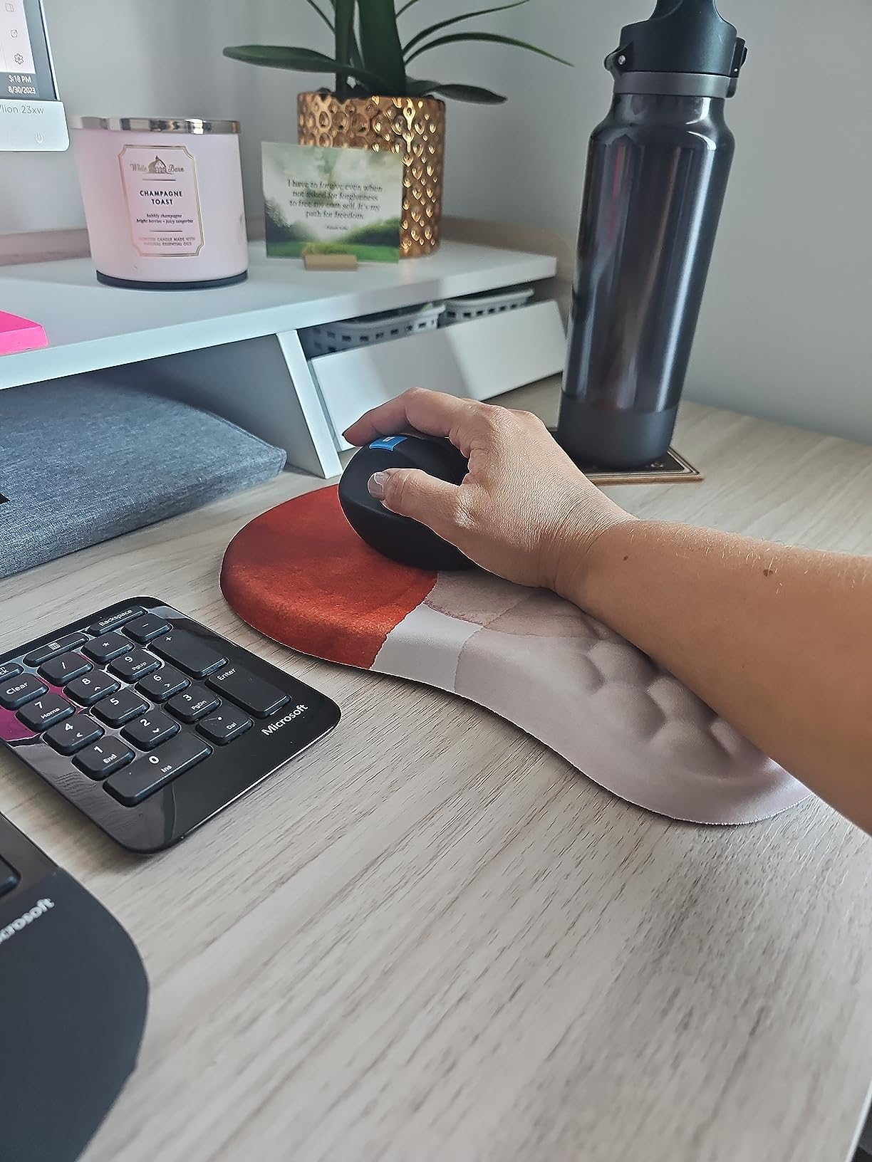Person's hand using an ergonomic mouse on a desk with office supplies