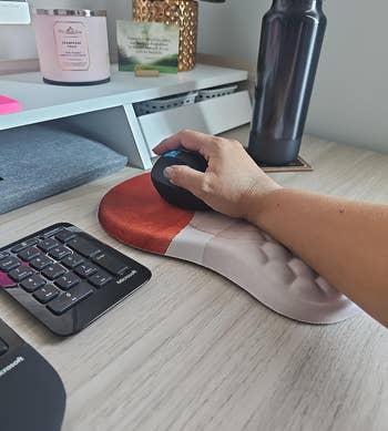 Person's hand using an ergonomic mouse on a desk with office supplies