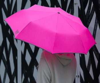 model standing underneath the travel umbrella that covers them completely