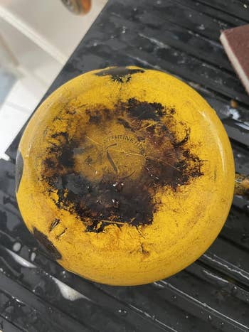 The bottommost  of a worn, yellowish  Dutch oven sits connected  a bedewed  surface, showing disposable   pain  marks