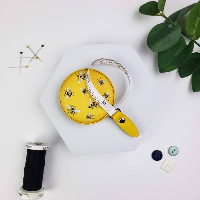 a pull measuring tape with a yellow bee print on it