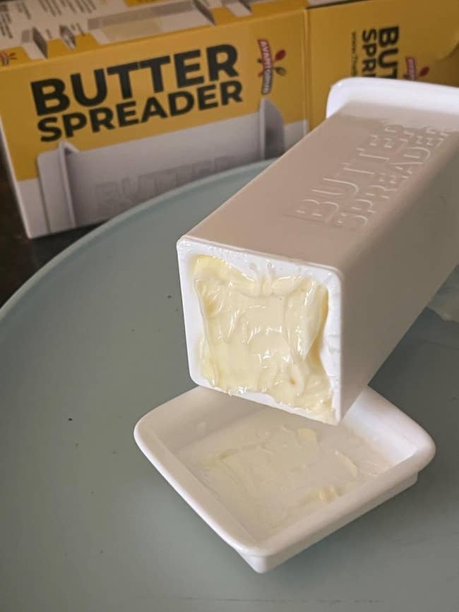 Butter spreader instrumentality dispensing food onto a tiny achromatic dish, with packaging disposable successful the background