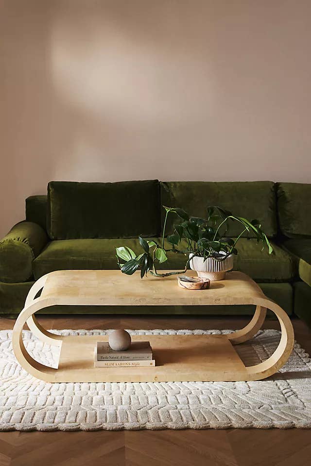 Modern living room with a unique curved wooden coffee table and a plush green sofa