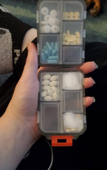 reviewer showing the opened black pill case with various compartments