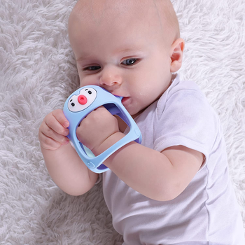 A baby sucking on the blue pacifier on their hand