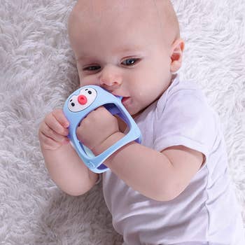A model baby sucking on the blue pacifier on their hand