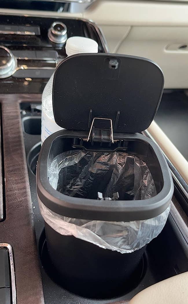 Black mini trashcan with trash bag in reviewer's cup holder