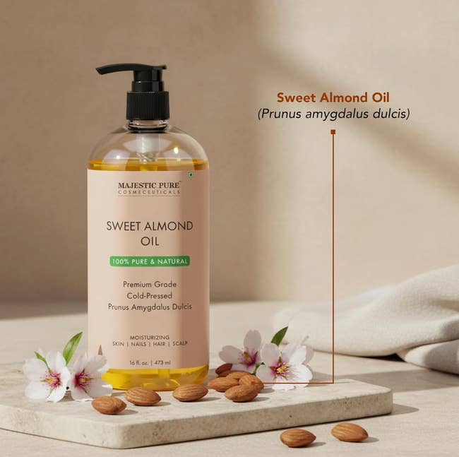 Majestic Pure Sweet Almond Oil vessel  with pump, surrounded by almonds and almond flowers. Text emphasizes it's premium, cold-pressed, and moisturizing