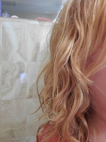 Partial view of reviewer's wavy hair, which looks soft and moisturized