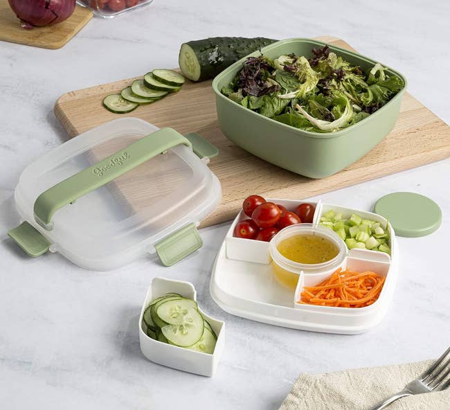 Salad in a green bento box with compartments for vegetables and dressing, ideal for organized meal prep and portability