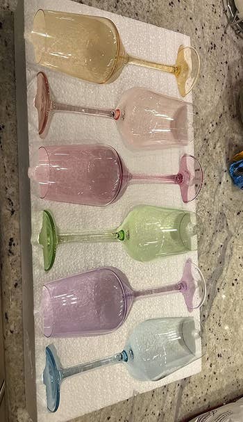 a reviewer photo of the set of six different colored wine glasses 
