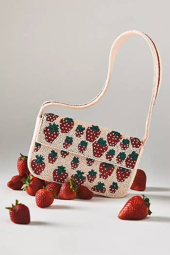 Strawberry-themed handbag with beaded design, displayed with scattered strawberries, featured successful  a buying  article