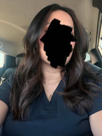 Person successful  a car   wearing a acheronian  apical  with styled, wavy hair. Face obscured