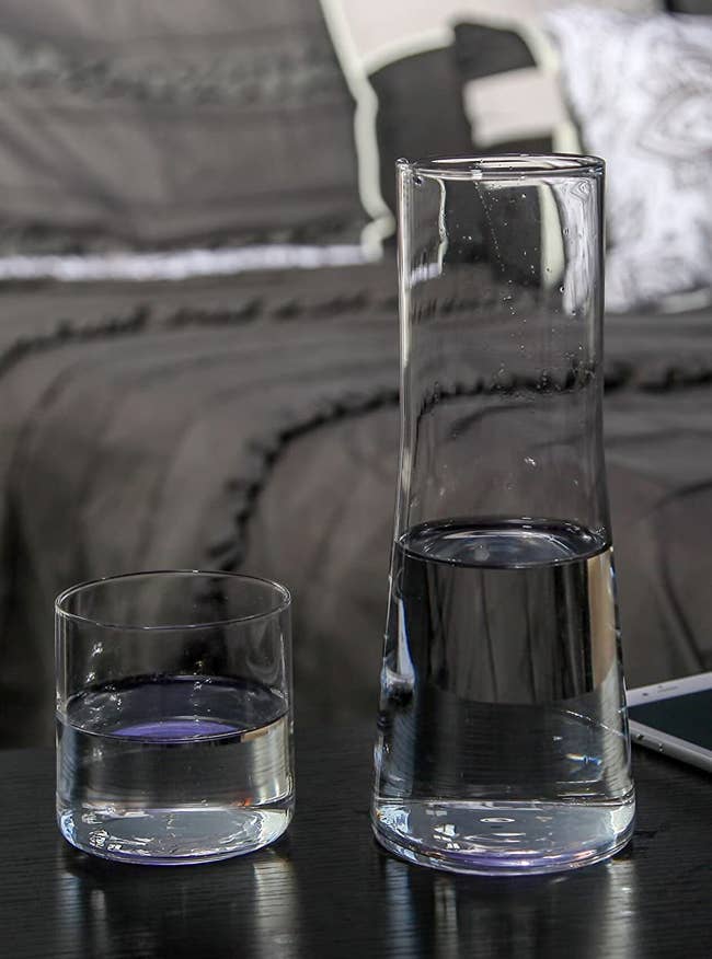 Glass carafe with cup filled with water in bedroom