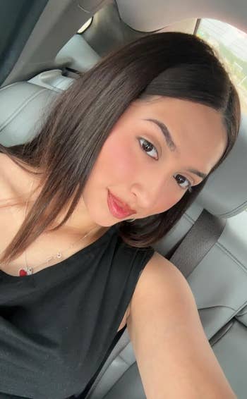 Person with agelong  hairsbreadth  taking a selfie successful  a car, wearing a sleeveless apical  and a necklace