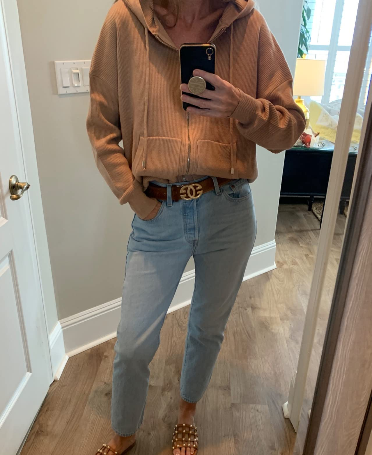 a reviewer wearing the hoodie in tan with the front tucked into jeans