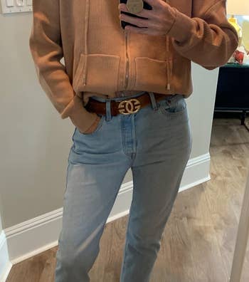a reviewer wearing the hoodie in tan with the front tucked into jeans 