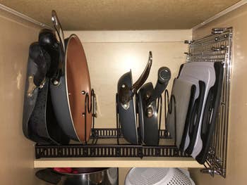 Reviewer image of pots, pans, and cutting boards in black organizer inside cabinet 