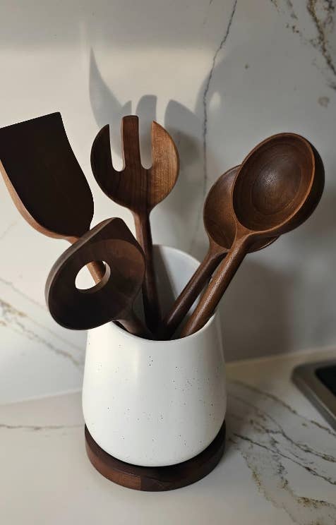 Wooden kitchen utensils in a white holder on a countertop