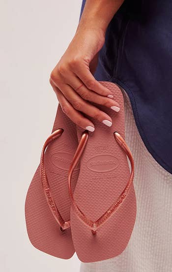 a model holding the square-toe flip flops in mauve 