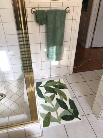 reviewer image of the leaf-print rug in front of a shower