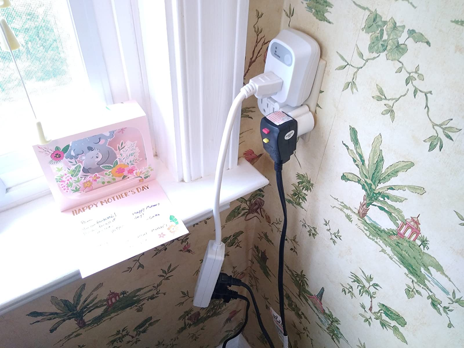the auto-shutoff outlet plugged into a wall with an extension cord that has hair tools plugged in