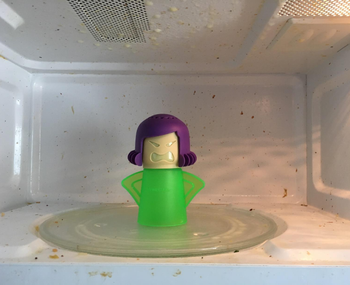 reviewer's before photo of the green angry mama in a dirty microwave