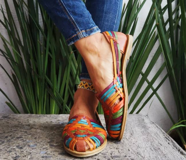 A model in rainbow woven sandals with the toes covered and a back heel strap 