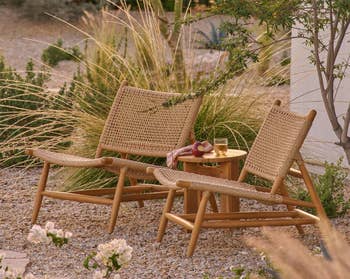 Two woven outdoor chairs with a tiny woody array betwixt them, holding a solid of achromatic vino and fruit, acceptable successful a serene plot scene