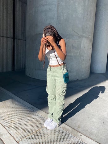 reviewer wearing green-gray cargo pants with a white cropped tank top and white air force 1s