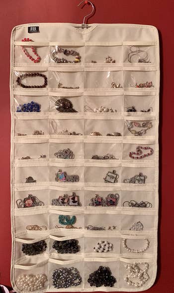 reviewer's beige hanging organizer full of jewelry items