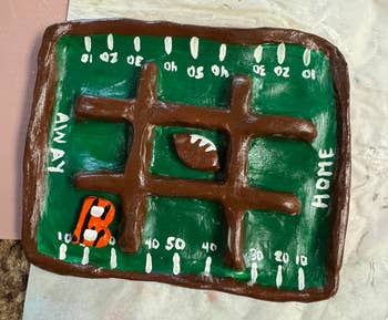 Clay shot tract with a tic-tac-toe design, featuring a tiny clay shot and an orangish jersey, labeled