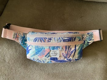 Reviewer image of blue, pink, and indigo plant covered fanny pack on a beige background