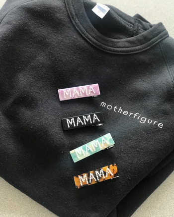 four MAMA barrettes in pink, black, blue, and brown on a sweatshirt