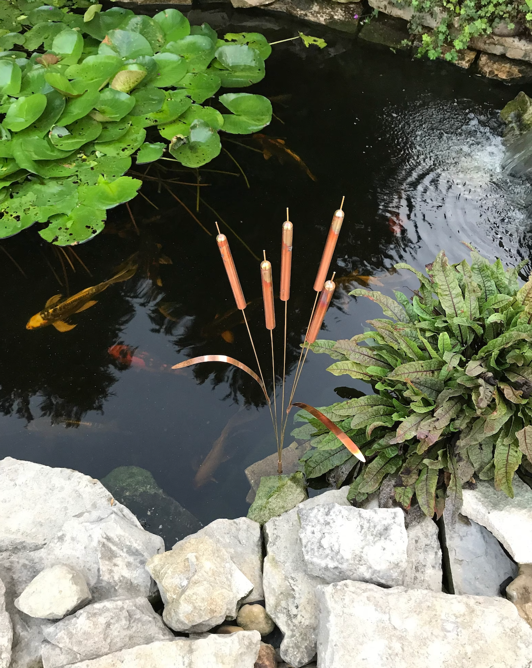 full size cattail wind chime placed in koi pond