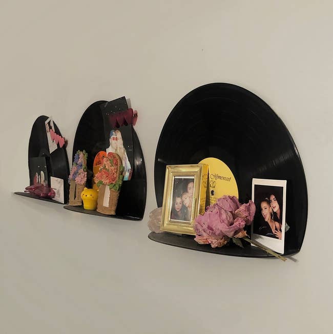 Vinyl records repurposed as wall shelves displaying various personal items and photographs