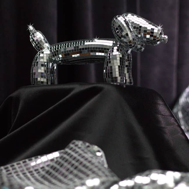 Reflective disco ball-style canine sculpture displayed connected a acheronian cloth, utilized successful a buying context