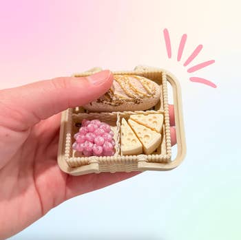 hand holding the fidget artifact  with a loaf of bread, grapes, and food  