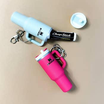 Portable lip balm holders with keychains attached displayed on a surface for easy carrying and access