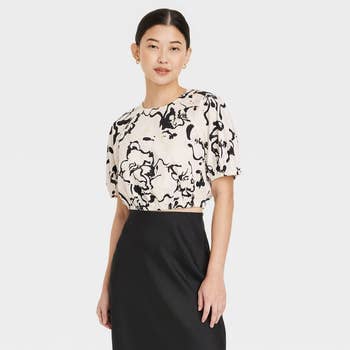 model in a patterned blouse and black skirt