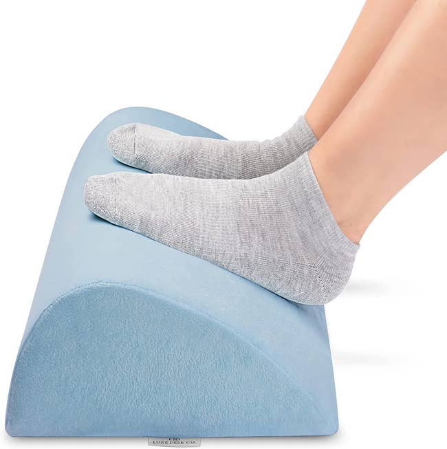 a model with their feet up on the teardrop-shaped blue cushion