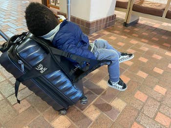 reviewers child sitting on seat attached to suitcase