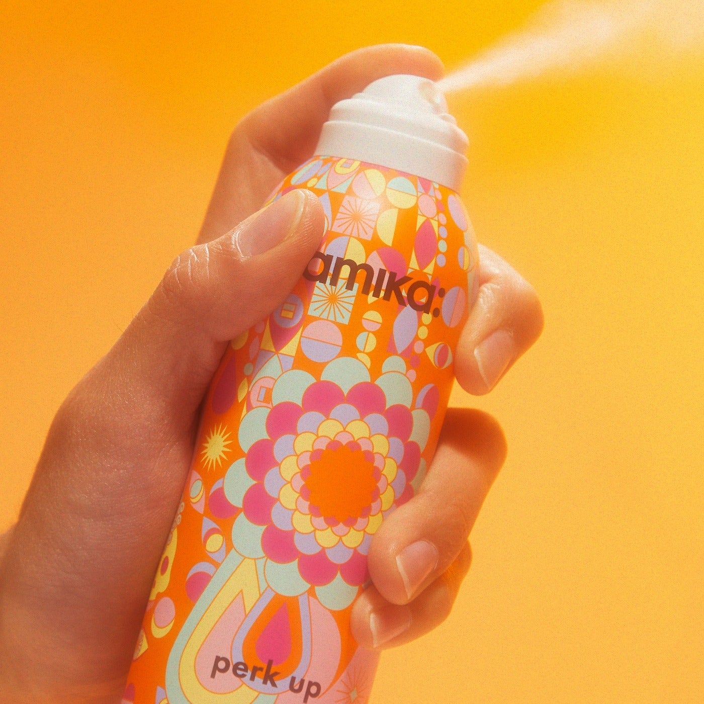 a model spraying the dry shampoo into the air