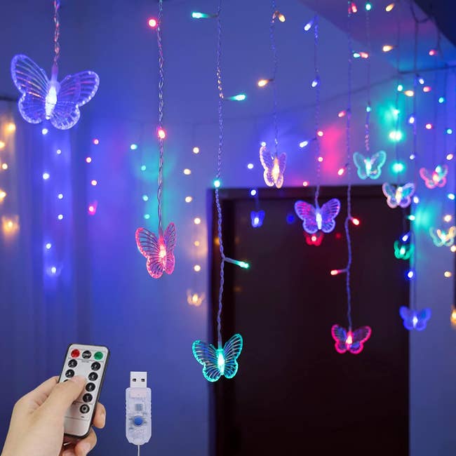 Butterfly shaped lights hanging from a ceiling being operated by a small remote 